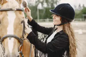 Reitkleidung - gut und günstig: Schicke Reiterfrau kämmt ihr Pferd